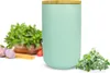 A turquoise ceramic storage jar with a wooden lid, placed on a white background with some ingredients like basil, garlic, spaghetti, and tomatoes. Náhľad obrázku produktu