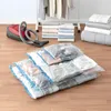Vacuum storage bags filled with clothes and bedding are laid out on a wooden floor next to a red vacuum cleaner. Voir les images du produit