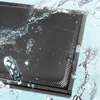 A close-up shot of a black kitchen hood filter with water splashing on it. Produktbild-Vorschau