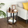 A round side table with a wood-look top and black metal legs, placed next to a sofa. Podgląd zdjęcia produktu
