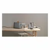 A gray toaster with a slice of bread in it, along with a pitcher and cups on a wooden table. Anteprima dell’immagine prodotto