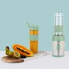 A portable blender and its accessories are displayed on a table with a light blue background. Produktbild-Vorschau