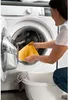 A woman is putting a yellow cloth into a washing machine. Anteprima dell’immagine prodotto