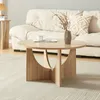 A round coffee table with a vase and cup on it, placed in front of a couch. Produktbild-Vorschau