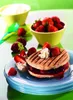 A close-up of a panini sandwich with strawberries and whipped cream, served on a blue plate, with bowls of strawberries and cream in the background. Podgląd zdjęcia produktu