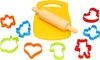 A collection of colorful plastic cookie cutters and a wooden rolling pin arranged around a yellow plastic cutting board on a white background. Podgląd zdjęcia produktu