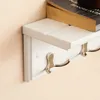 A close-up of a white wall-mounted shelf with metal hooks below. Produktbild-Vorschau