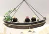 A wooden wine rack shaped like a boat, hanging from chains, with three wine bottles and some greenery. Produktbild-Vorschau