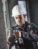 A man is using a power drill to drill into a wooden plank. Produktbild-Vorschau