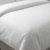 A close-up view of white hotel bedding with a subtle striped pattern. Produktbild-Vorschau