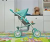 A doll stroller is shown in a room with toys and furniture in the background. Produktbild-Vorschau