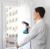 A man is using a handheld garment steamer on white curtains in front of a window. Produktbild-Vorschau