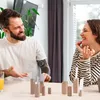 A couple is sitting at a table and playing a game with wooden figures. Voir les images du produit