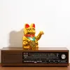 A golden lucky cat figurine sits on top of a vintage wooden radio. Produktbild-Vorschau