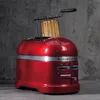 A red KitchenAid toaster with toast in it, set against a dark gray concrete wall. Anteprima dell’immagine prodotto