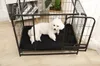A white dog is lying on a black training pad inside a black metal dog crate. Náhľad obrázku produktu