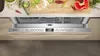 A close-up view of a dishwasher's control panel and the top rack, with food ingredients visible on a cutting board above. Produktbild-Vorschau