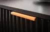 A close-up view of a black nightstand with an orange drawer pull. Produktbild-Vorschau