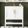 A white bathroom vanity with gold hardware is shown against a dark green wall and a patterned floor. Voir les images du produit