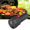 A close-up of a black electric grill motor in the foreground, with a barbecue grill full of food in the background. Produktbild-Vorschau