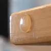 A close-up of a clear, oval-shaped bumper on a wooden surface. Produktbild-Vorschau
