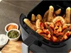 An air fryer filled with seasoned potatoes and sweet potatoes, with small bowls of spices in the foreground. Náhled obrázku produktu
