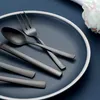 A set of black cutlery is arranged on a dark blue plate. Podgląd zdjęcia produktu