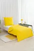 A yellow duvet set on a single bed with a white headboard, a small bedside table with a lamp, and a rug on the floor. Podgląd zdjęcia produktu