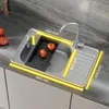 A stainless steel kitchen sink with a faucet and a black dish rack containing two tomatoes. Produktbild-Vorschau