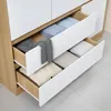 A close-up view of open drawers in a wardrobe, showing neatly folded clothes. Anteprima dell’immagine prodotto