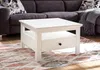 A white coffee table with a drawer is placed on a patterned rug in front of a dark gray sectional sofa. Produktbild-Vorschau