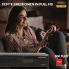 A woman is sitting on a couch watching TV and eating popcorn. A satellite receiver is in the foreground. Produktbild-Vorschau