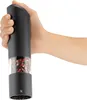 A hand holding a black electric salt and pepper grinder filled with peppercorns. Produktbild-Vorschau