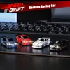 Four miniature remote control drift cars are displayed on a dark surface in front of a laptop keyboard. Náhled obrázku produktu