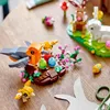 A close-up of a LEGO Creator bird's nest set with three toy birds and Easter eggs, placed on a wooden table with craft supplies. Produktbild-Vorschau