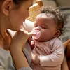 A mother is holding her baby and giving the baby a pacifier. Produktbild-Vorschau