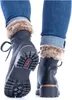 A close-up view of a person wearing black lace-up boots with fur trim and blue jeans, shown from the back. Anteprima dell’immagine prodotto