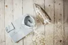 A light blue collared shirt is laid flat next to a silver steam iron on a light wooden surface, with small white dried flowers scattered around. Produktbild-Vorschau