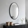 A mirror hangs above a dresser with baskets and books. Produktbild-Vorschau
