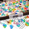 A collection of colorful resin alphabet letter keychains and other shaped keychains with tassels, laid out on a surface with newspaper print. Produktbild-Vorschau