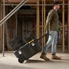 A man is pulling a rolling tool chest on a construction site. Anteprima dell’immagine prodotto