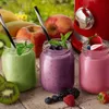 Three mason jars filled with colorful smoothies, surrounded by fresh fruits and a red blender in the background. Voir les images du produit