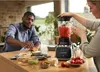 A man and a woman are in a kitchen preparing food with a blender. Produktbild-Vorschau