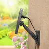 A solar panel is mounted on a wall, angled towards a garden with flowers. Produktbild-Vorschau