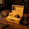 A wooden storage box with a combination lock, open to reveal glass jars and accessories, sits on a wooden table next to books. Produktbild-Vorschau