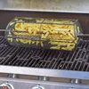 A rotisserie basket filled with french fries sits on a grill. Podgląd zdjęcia produktu