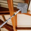 A cleaning tool with a brush head on an extendable pole is being used to clean cobwebs from the rafters of a wooden structure. Voir les images du produit