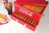 A red and white Coca-Cola branded hot dog steamer filled with hot dogs and buns, with a glass of Coca-Cola and a hot dog on a plate nearby. Anteprima dell’immagine prodotto