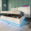A white upholstered bed with storage is shown with the mattress lifted, revealing storage space. Blue LED lights illuminate the base of the bed. Produktbild-Vorschau