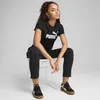 A young woman is sitting on a white chair, wearing a black Puma t-shirt and black pants. She is looking at the camera with a neutral expression. Anteprima dell’immagine prodotto
